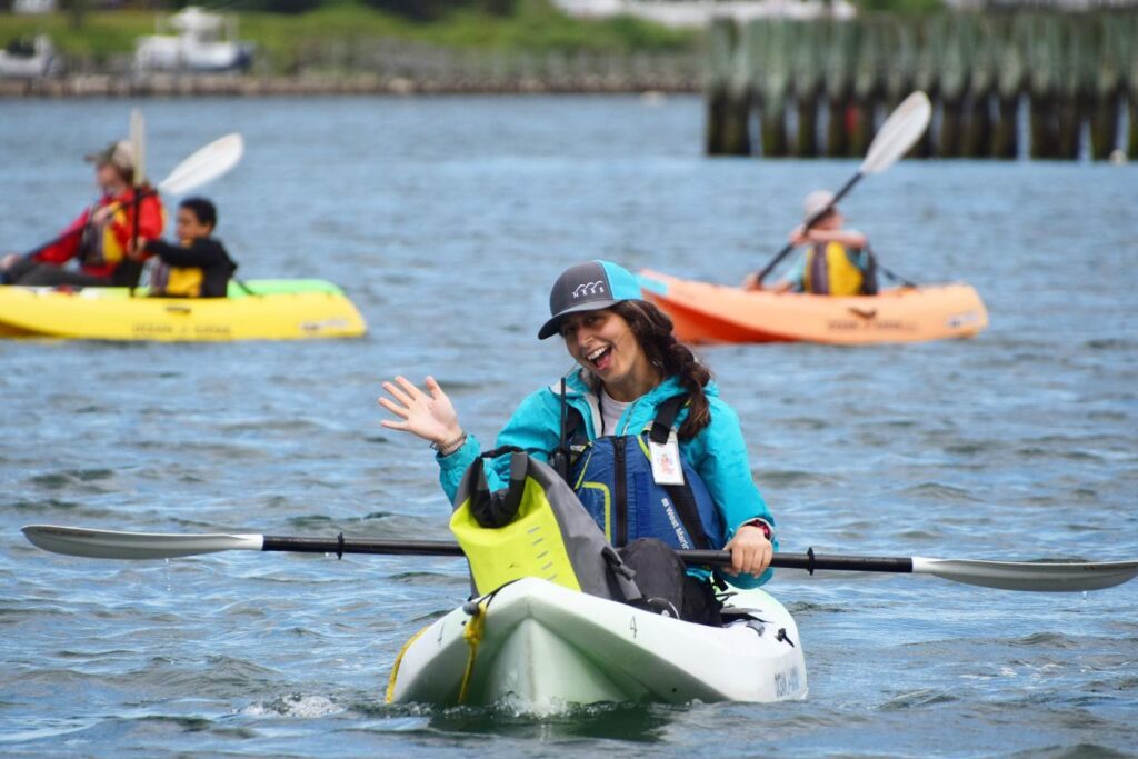 Young person in kayak, waving and smiling