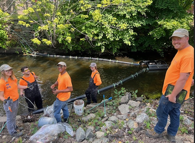 Group of people on a riverbank, seemingly collecting scientific data